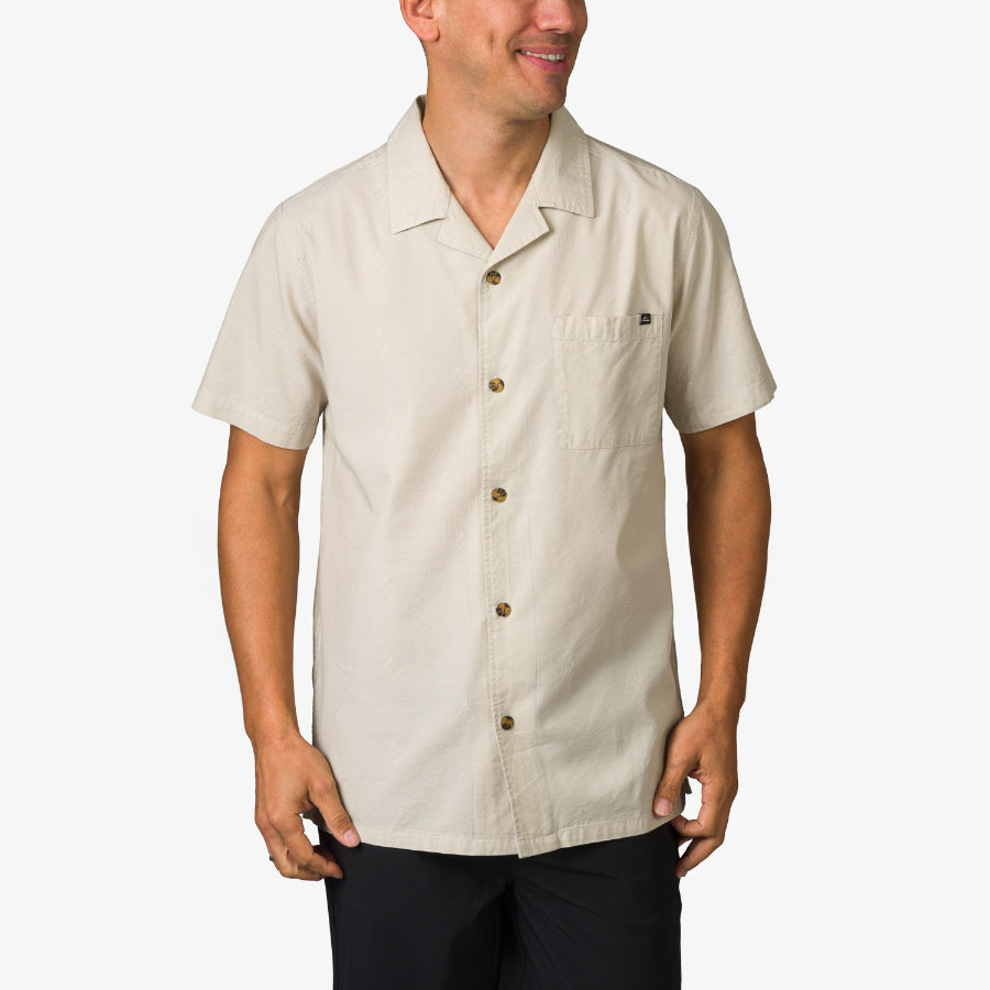 Man wearing a beige Harold Camp Shirt with short sleeves and front buttons, styled for casual beachwear comfort.