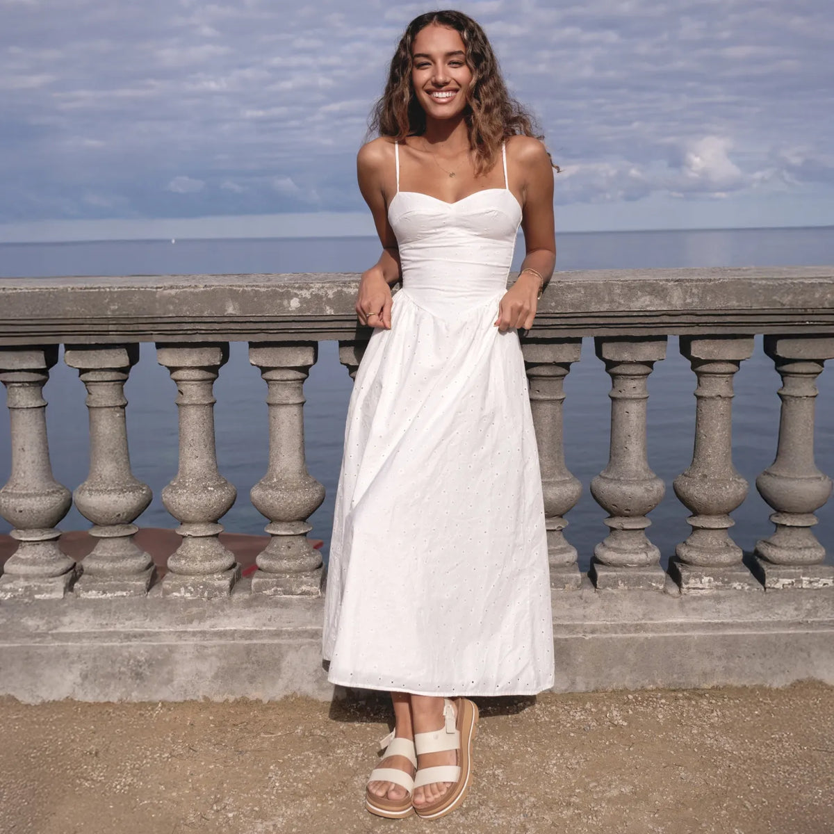 Woman wearing Vista Luxe Liah sandals facing forward, standing on a beachside promenade, showcasing comfort and style.