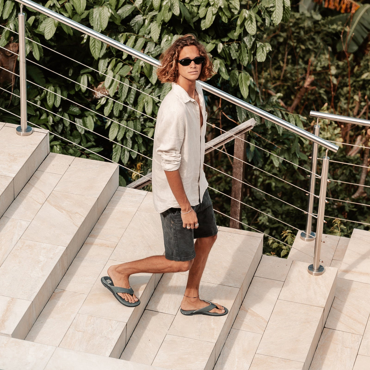 Man walking down stairs wearing Offshore grey flip flops facing right, showcasing water-friendly, extra cushion sandals.