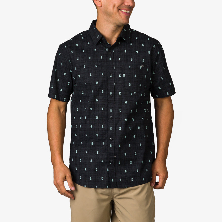 Man wearing Chaplin Classic Shirt in black with subtle pattern, smiling, shown from front, styled for casual beachwear.