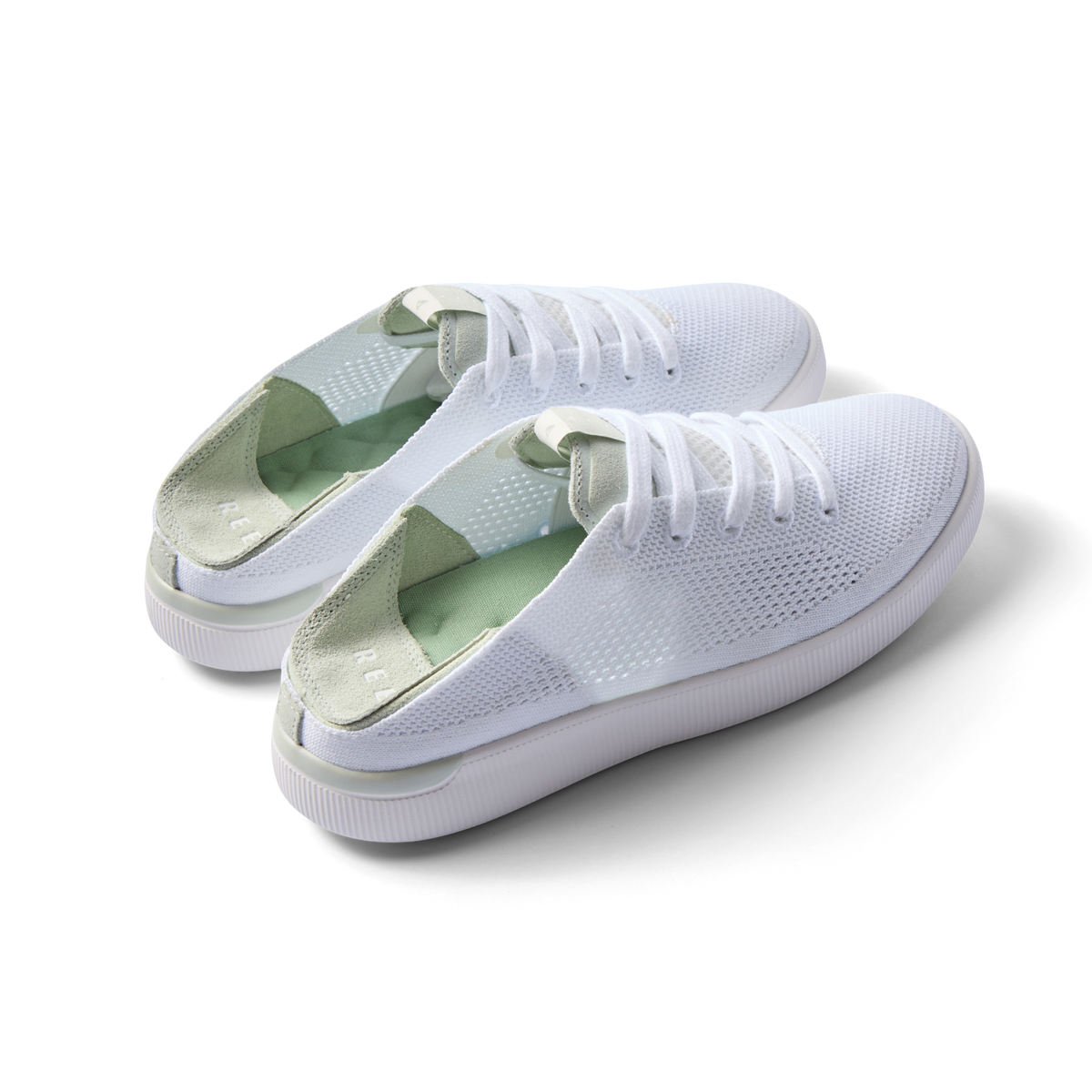 Pair of Reef Neptune shoes facing right, featuring white and dusty sage colors, knit material, and cushioned arch support.