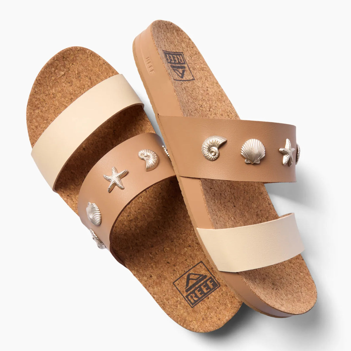 Cushion Vista women's sandals facing left with tan cork footbeds, cream and tan straps, and shell embellishments.