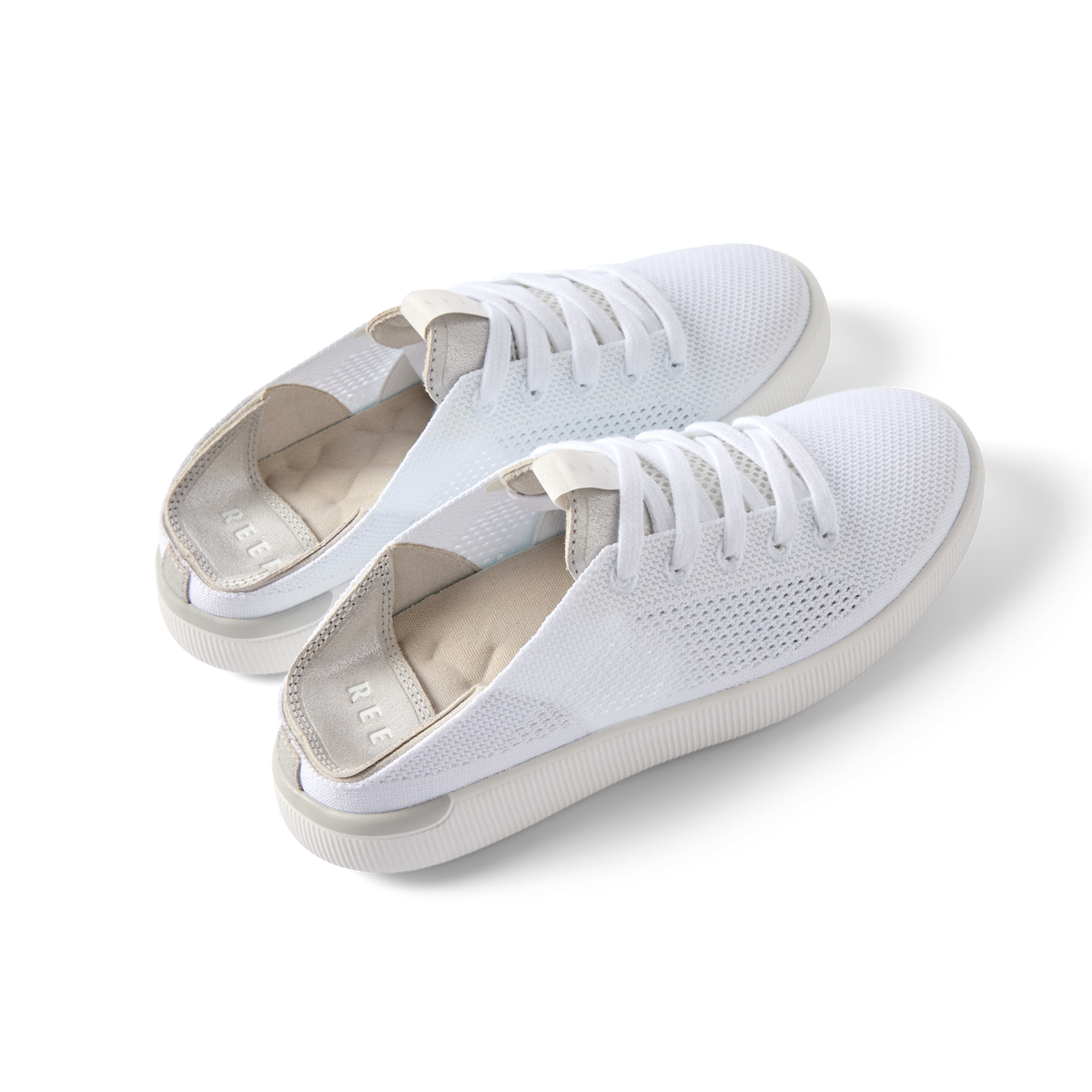 Pair of white Reef Neptune shoes facing right showing top and side, featuring breathable mesh and cushioned arch support.