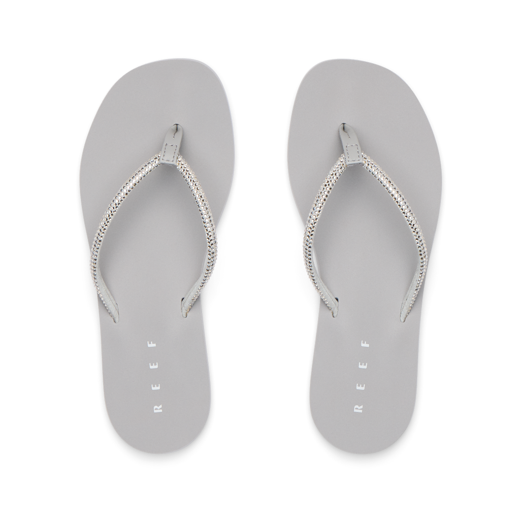 Bliss Bling Fling silver women's flip flops facing up, featuring surf-inspired comfort and soft cushioning for the beach.