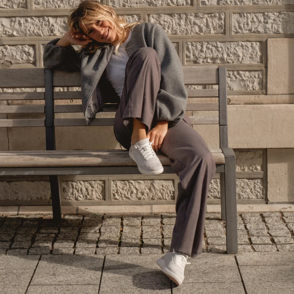 Woman sitting on bench wearing Shoreline Palisades sneakers facing forward, showcasing cushioned, lightweight design.