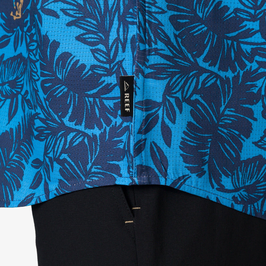 Close-up of the hem and label on the blue Tyson Classic Shirt with dark tropical leaf print for men.