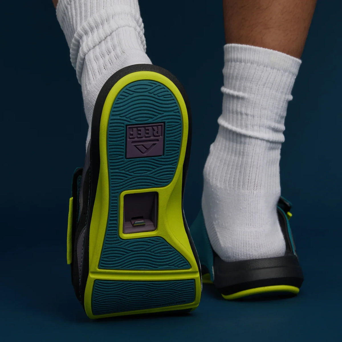 Cruiser Slide men's sandals showing the sole with green accents, worn on feet facing away, highlighting arch support design.