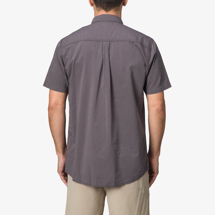 Back view of a man wearing a grey Collins Ss Wvn Shirt with short sleeves, casual fit for beach and active lifestyle.