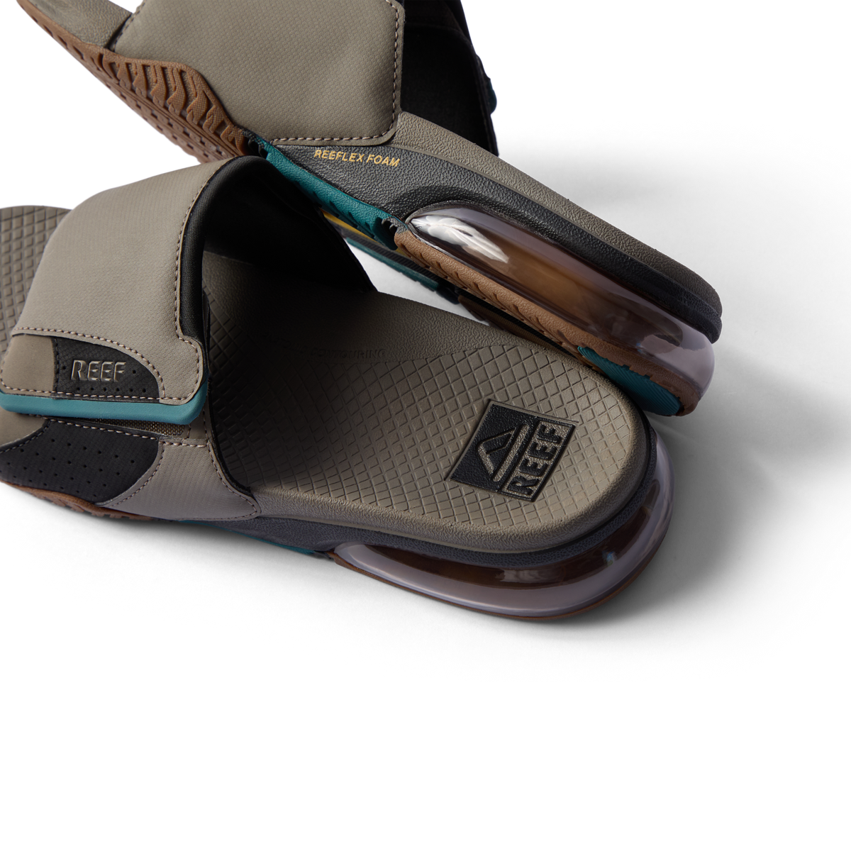 Close-up of tan slides facing right showing textured footbed, REEF logo, and transparent cushioned sole with REEFLEX foam support.
