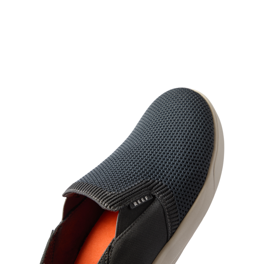 Neptune Slip-On men's black and white shoe facing left, showing breathable mesh upper and cushioned sole close-up.