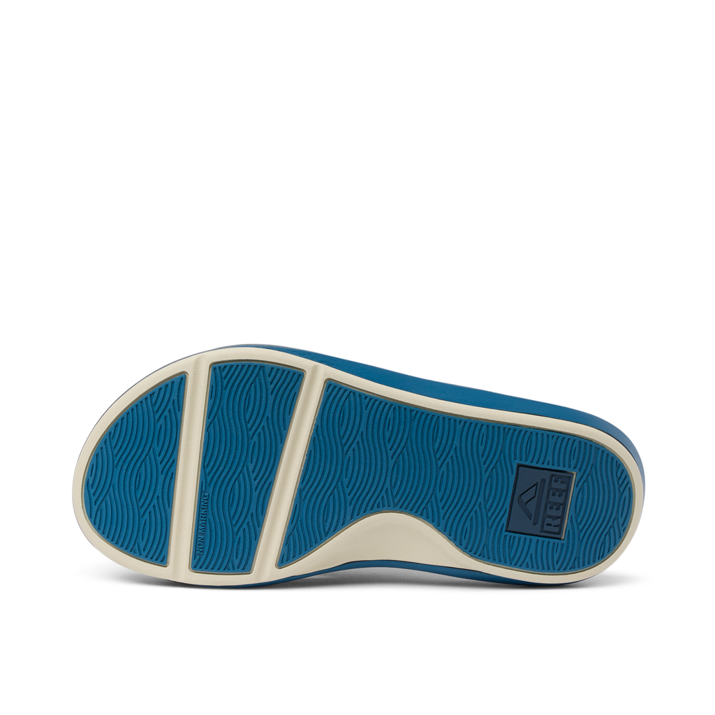 Cruiser men’s shoe sole facing up, showing blue rubber outsole with wave pattern and brand logo, surf-inspired comfort design.